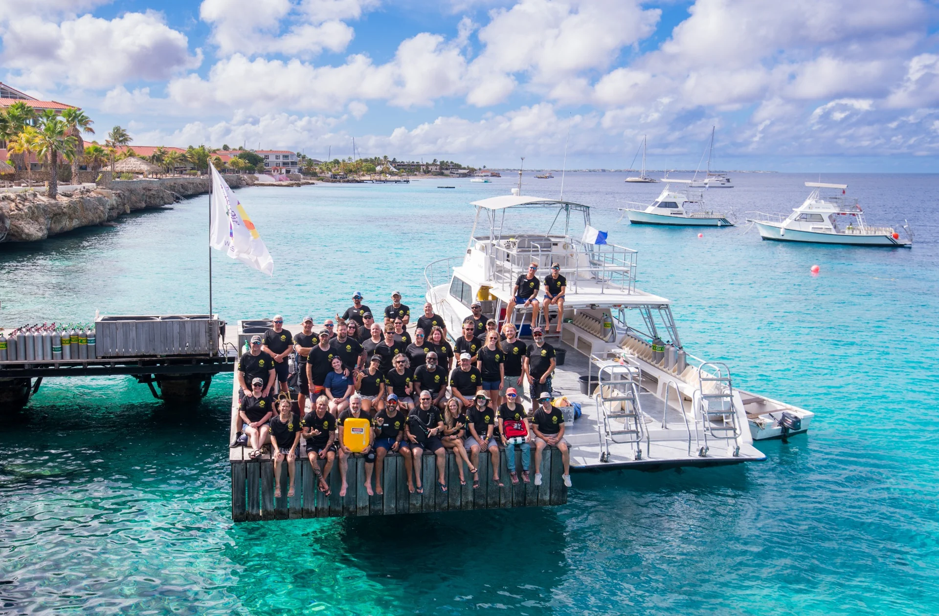 Divers gathered on a dock beside boats and turquoise Caribbean water in Bonaire